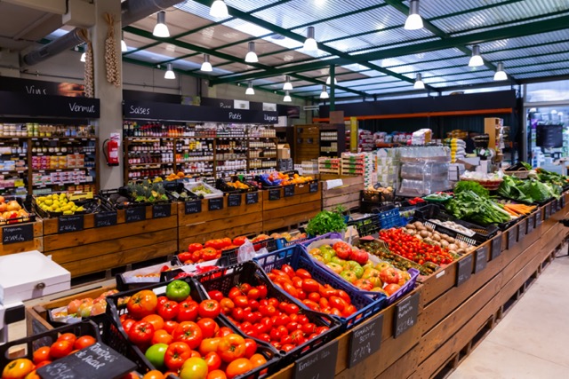 Independent grocer reviewing grocery store POS system FAQ on FlexRetail tablet showing features and pricing comparison for independent stores