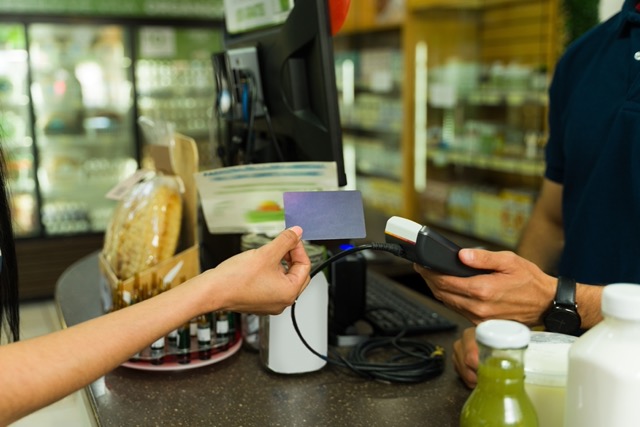 Independent grocery store owner comparing affordable POS system pricing with FlexRetail showing low-cost point of sale features and satisfaction guarantee