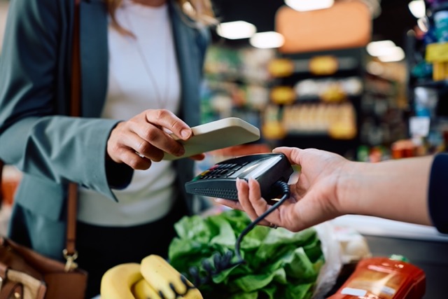 Independent grocery store checkout lane showing POS system reliability backup procedures and staff training for handling point of sale downtime during peak hours