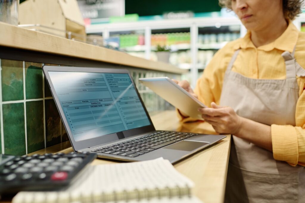 Independent grocer evaluating a grocery POS demo with a vendor representative in a store setting