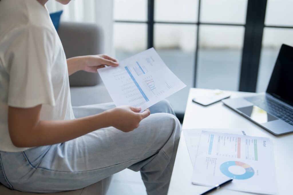 Grocery store owner comparing multi-location POS reporting dashboards while planning a second store