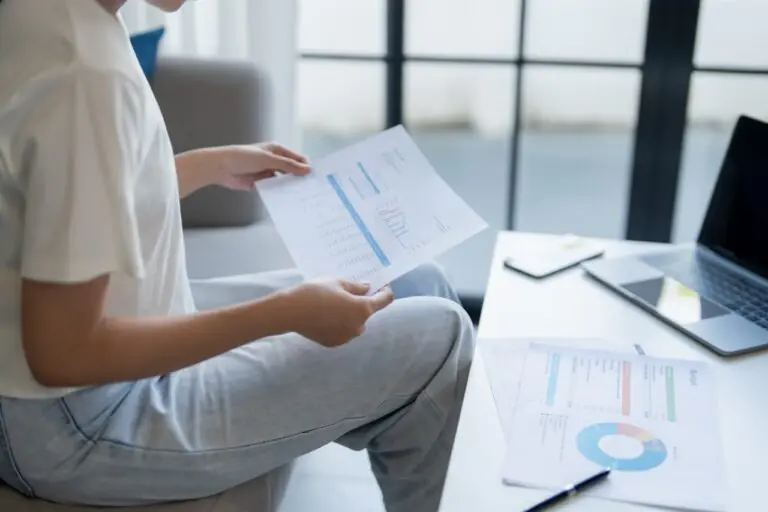 Grocery store owner comparing multi-location POS reporting dashboards while planning a second store