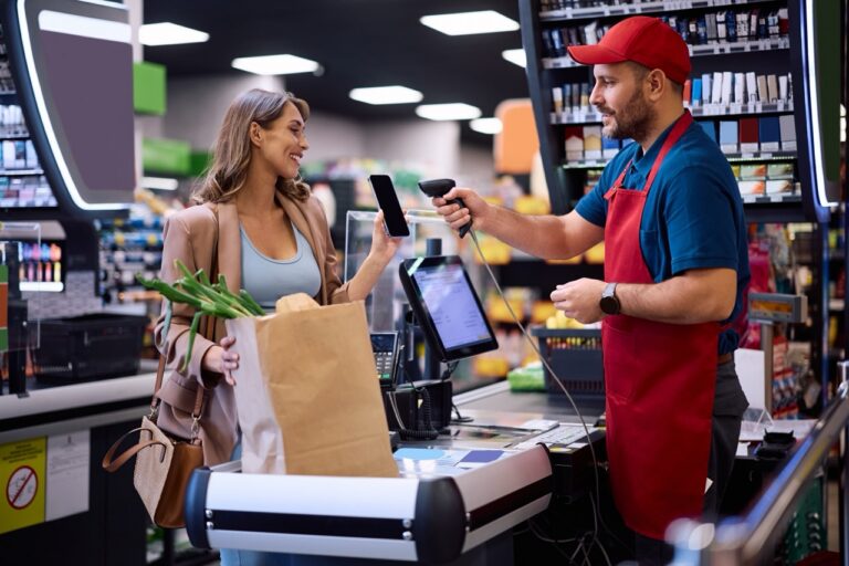 Grocery cashier scanning a digital coupon barcode from a customer's phone at checkout