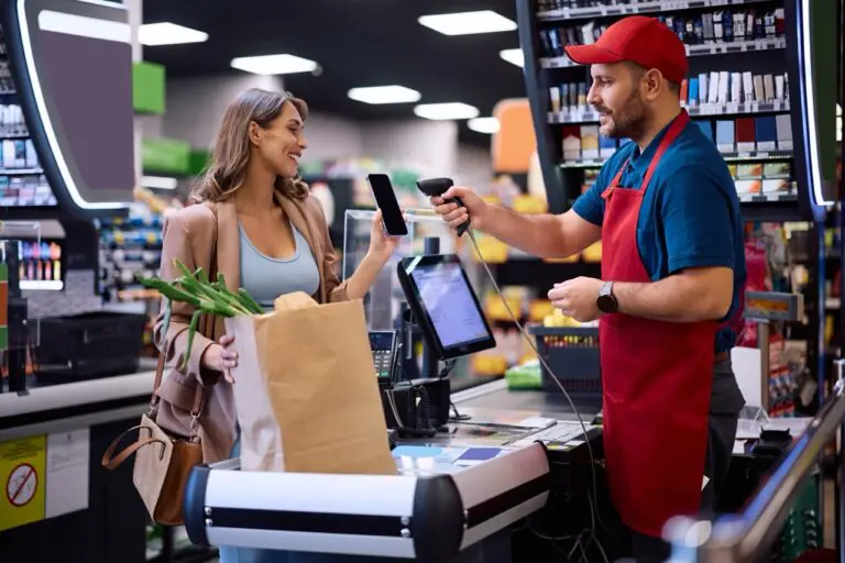 Grocery cashier scanning a digital coupon barcode from a customer's phone at checkout