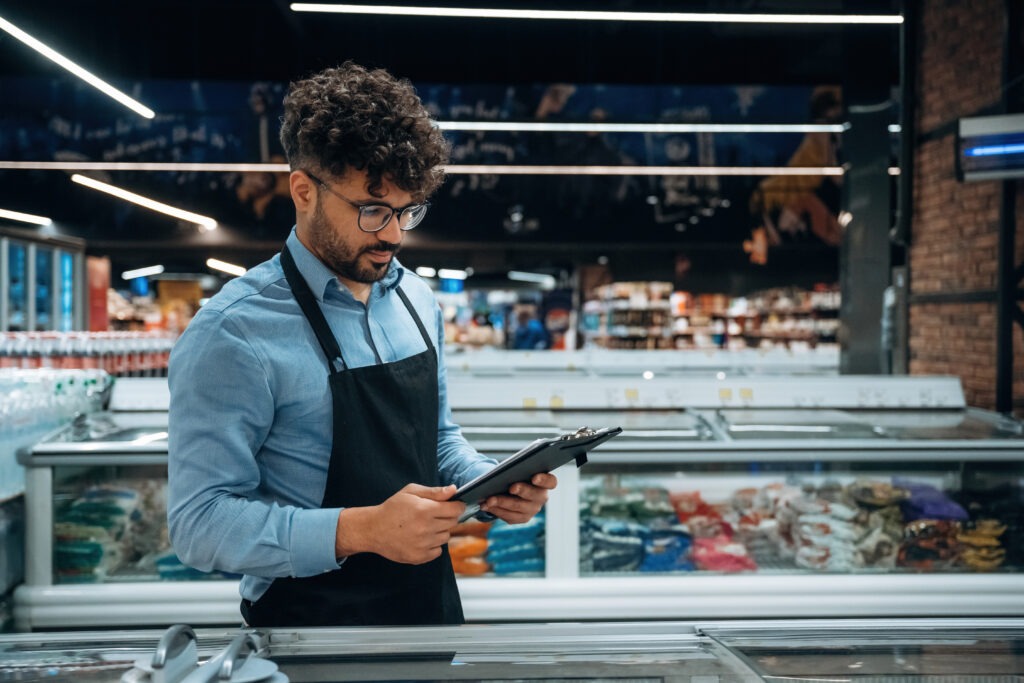 Grocery store manager comparing online ordering search data with in-store product placement