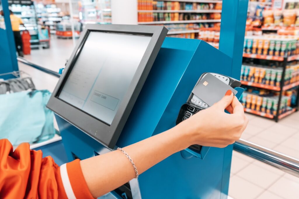 Grocery store owner inspecting a card terminal for PCI compliance and payment security