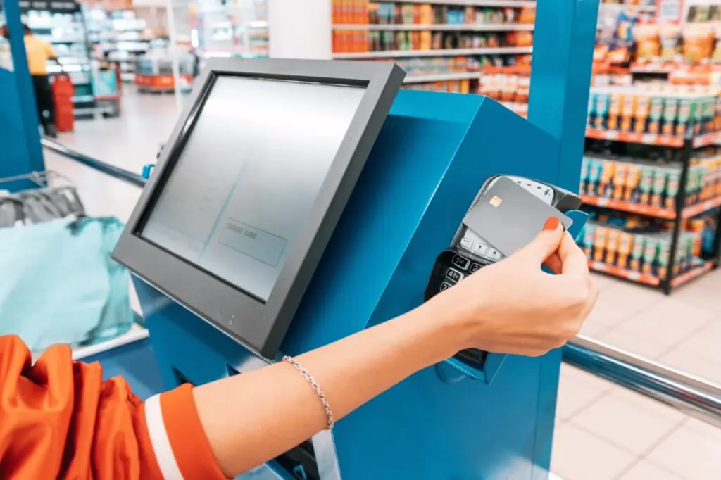 Grocery store owner inspecting a card terminal for PCI compliance and payment security