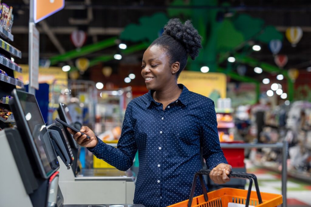 Shopper scanning groceries at a self-checkout lane, where self-checkout shrink can occur