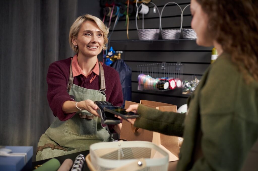 Grocery store employee handing a gift card to a customer at the counter as part of a grocery store gift card program