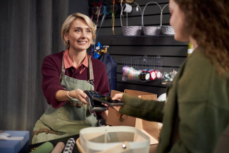 Grocery store employee handing a gift card to a customer at the counter as part of a grocery store gift card program