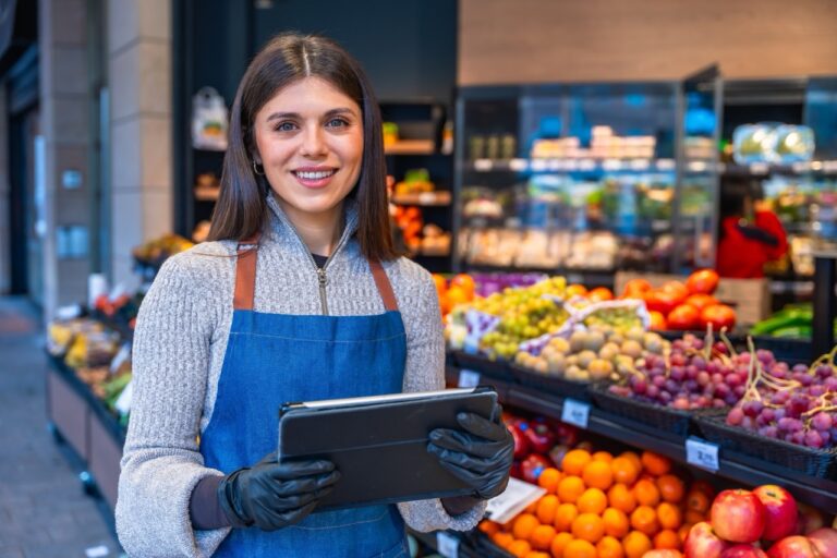 Grocery employee holding a tablet in the produce department to review grocery loyalty segmentation data