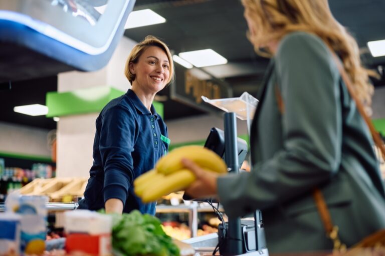 Grocery cashier helping a customer at checkout, an example of grocery customer service recovery