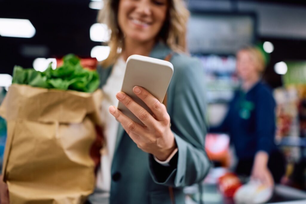 Grocery shopper checking a digital receipt on her smartphone at checkout in a paperless grocery store