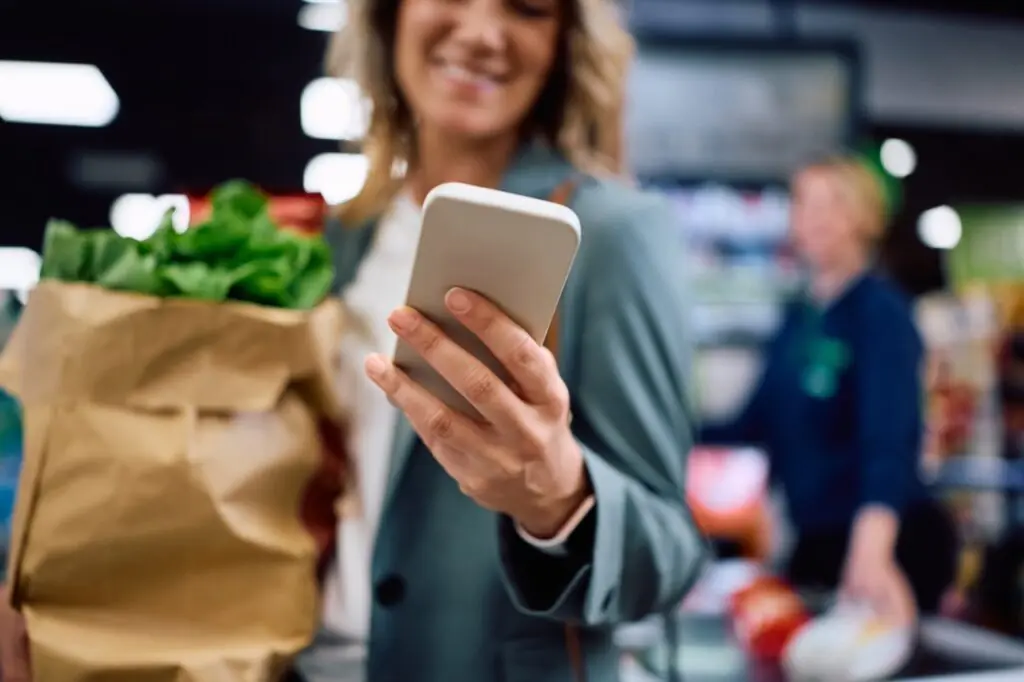 Grocery shopper checking a digital receipt on her smartphone at checkout in a paperless grocery store